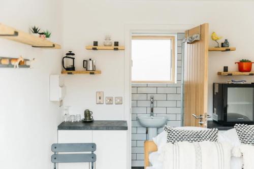 a room with a kitchen with a sink and a television at Delores Eco-Pod / Treehouse, Walk to Cabot Circus in Bristol