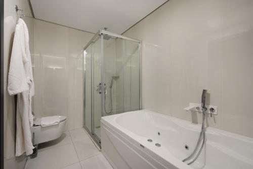 a white bathroom with a shower and a tub at DDK Hotel Duhok in Duhok