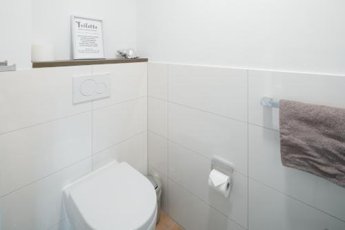 a white bathroom with a toilet and a towel at Penthouse NorderNice in Norderney