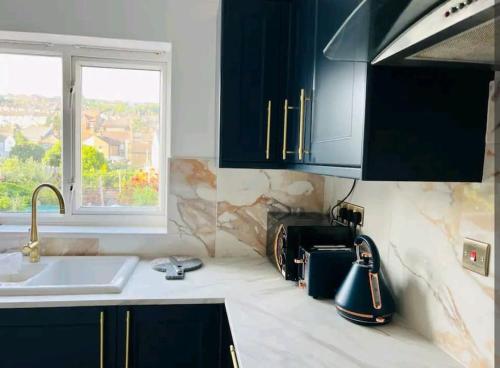 uma cozinha com armários pretos, um lavatório e uma janela em Modern 2 bedroom flat by Dover Port, Castle& Sea! em Kent