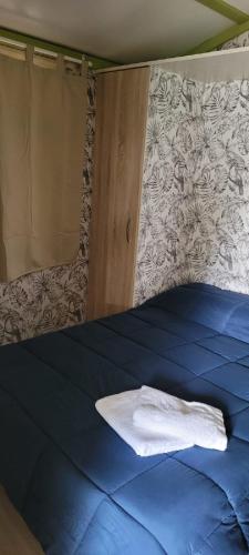 a bed with a blue comforter with a towel on it at Camping Costa Blanca in El Campello