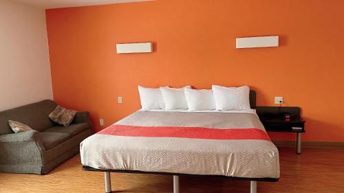 a bedroom with a bed with an orange wall at Motel 6-Regina, SK in Regina