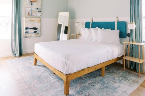 a bedroom with a large white bed with a blue headboard at Unit 124 - The Strand 2 Bed - Cation on the Guadalupe in New Braunfels