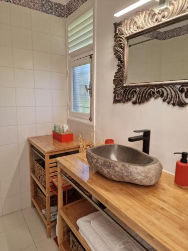 La salle de bains est pourvue d'un lavabo en pierre et d'un miroir. dans l'établissement Appartements de Luxe . Propriété de Luxe, à Baie-Mahault