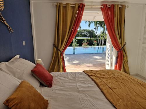 a bed with two pillows and a window with a patio at Appartements de Luxe . Propriété de Luxe in Baie-Mahault