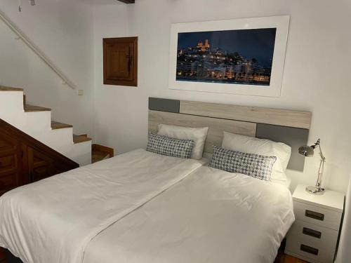 a bedroom with a white bed with a picture above it at Classical corner town house in historical centre in Altea