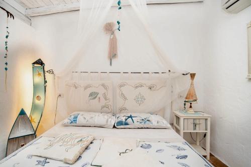 a bedroom with a white bed with a canopy at La Casa delle Conchiglie in Capo Coda Cavallo