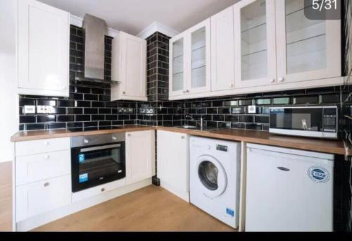 a kitchen with white cabinets and a washer and dryer at The Sherborne Boutique in London