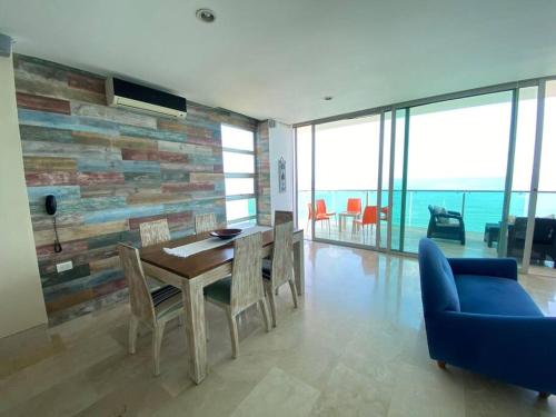 a dining room with a table and chairs and a wall of windows at Las 4 Estaciones Alojamientos de Ensueño Coveñas in Coveñitas