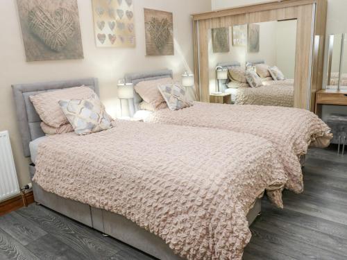 a bedroom with two beds and a mirror at Dale Cottage in Oldham