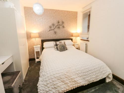 a bedroom with a white bed and two lamps at Moor Cottage in Oldham