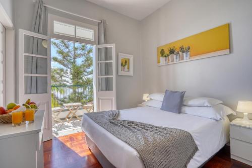 a white bedroom with a bed and a balcony at Vila Camacho Guest House in Funchal