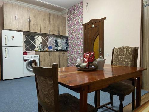 a kitchen with a wooden table and a white refrigerator at Hostel Highway in Samarkand
