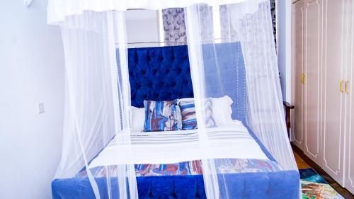 a bedroom with a blue bed with a canopy at Primal apartment at Embakasi, Nairobi, Kenya. in Nairobi