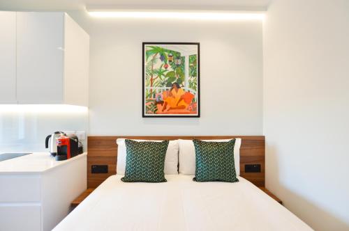 um quarto com uma cama com almofadas verdes e brancas em West Hampstead Serviced Apartments by Concept Apartments em Londres