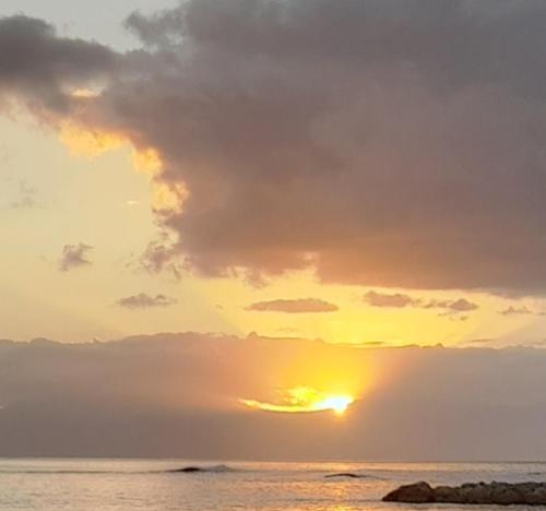 a sunset over the ocean with the sun setting at Joli appartement St François Guadeloupe in Courcelles Sucrerie