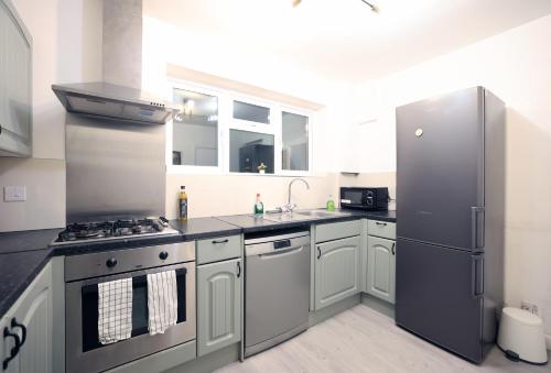 a kitchen with a stove and a refrigerator at Bath City Skyline Spacious 3 Bed House for family in Bath