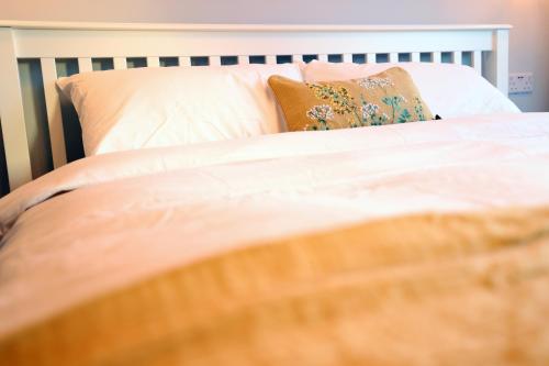 a bed with white sheets and pillows at Bath City Skyline Spacious 3 Bed House for family in Bath