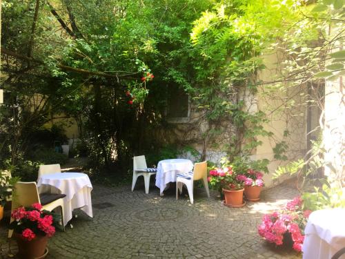 eine Terrasse mit weißen Tischen, Stühlen und Blumen in der Unterkunft Kindl 's Low Budget in Wien