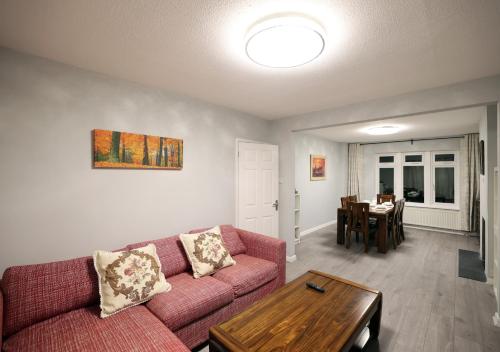 a living room with a red couch and a table at Bath City Skyline Spacious 3 Bed House for family in Bath