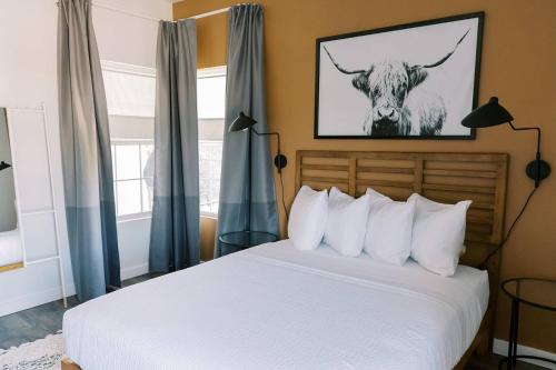 a bedroom with a bed with a cow picture on the wall at Unit 222 - The Lyndon 1 Bed - Cation on the Guadalupe in New Braunfels