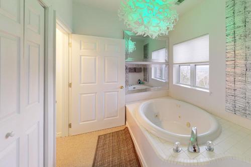 baño grande con bañera y lámpara de araña. en Star Ridge Retreat, en Eureka Springs