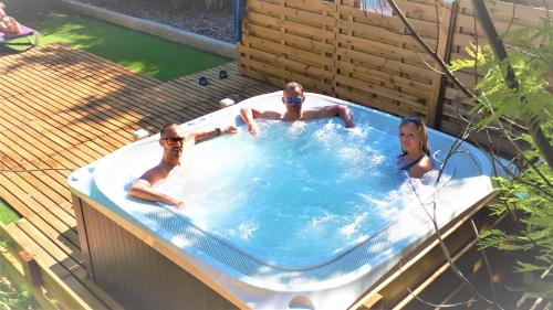 Tre uomini stesi in una vasca idromassaggio in un cortile di Hotel Les Jardins de Bormes a Bormes-les-Mimosas