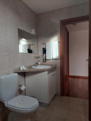a bathroom with a toilet and a sink and a mirror at Varandas da Ria in Costa Nova