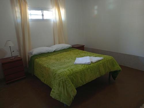 1 dormitorio con 1 cama verde y 2 toallas en La Carmela en San Rafael