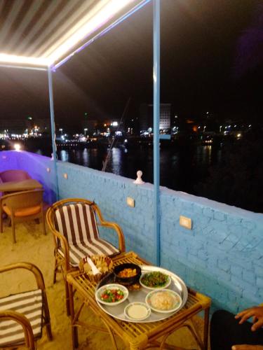 a table with plates of food on a balcony at night at Jamaica Guest House in Aswan
