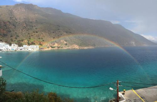 a rainbow over a body of water with a mountain at Hotel Porto Loutro on the Hill in Loutro