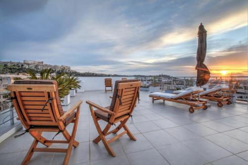 a balcony with chairs and an umbrella and water at Acropolis Panorama View Penthouse with Private Terraces A Contemporary Parthenon in Athens