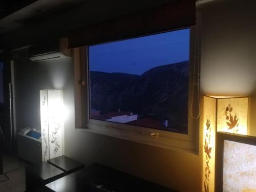 una camera con una grande finestra con vista sulle montagne di Πολυτελή Μεζονέτα με Τζάκι και υπέροχη θεά a Delfi