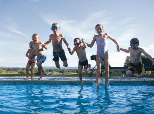a group of children jumping into a swimming pool at Woolley Grange - A Luxury Family Hotel in Bradford on Avon