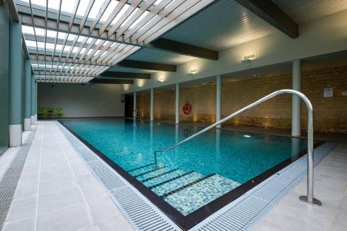 a large swimming pool with blue water in a building at Woolley Grange - A Luxury Family Hotel in Bradford on Avon