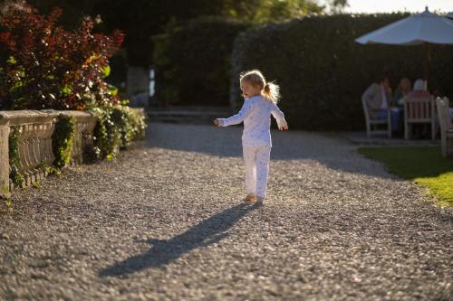 a little girl is standing on a gravel road at Woolley Grange Hotel in Bradford on Avon