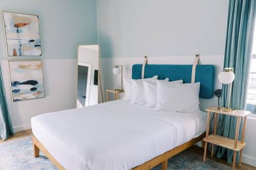 a bedroom with a white bed with a blue wall at Unit 213 - The Strand 2 Bed - Cation on the Guadalupe in New Braunfels
