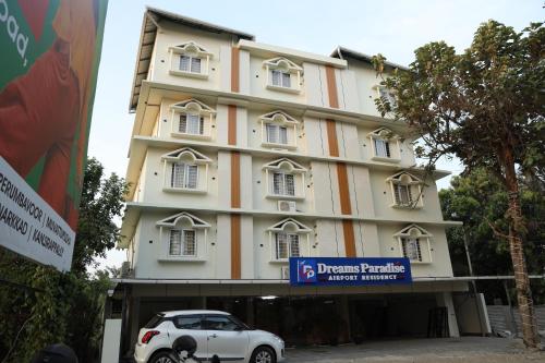 a white car parked in front of a building at DREAMS PARADISE AIRPORT RESIDENCY in Nedumbassery