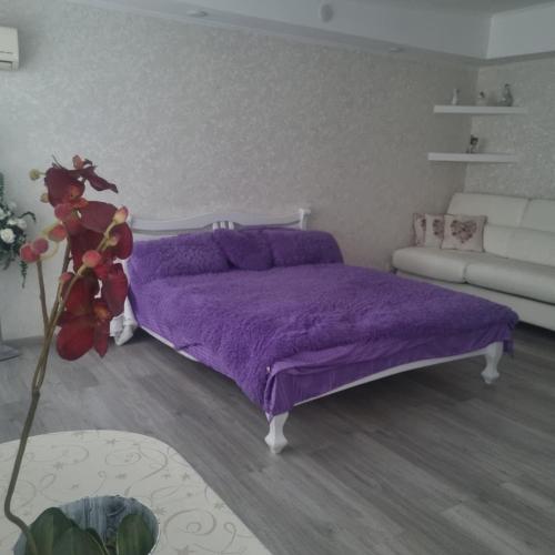 1 dormitorio con cama morada y sofá en White apartament, en Kremenchuk