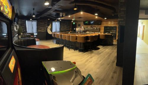 a restaurant with a bar with tables and chairs at Ramada by Wyndham Estevan in Estevan