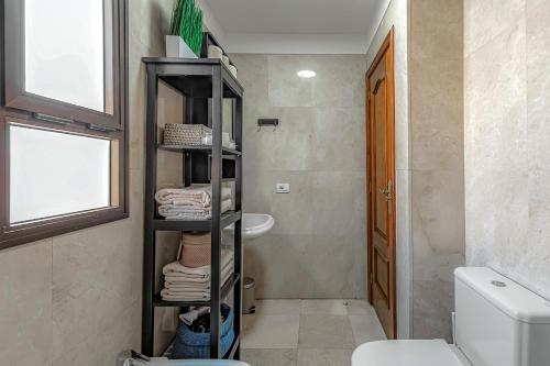 a bathroom with a toilet and a shelf with towels at Casa del Mar in Callao Salvaje