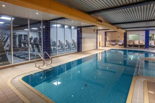 a large swimming pool in a building with a gym at Chesford Grange Hotel in Kenilworth