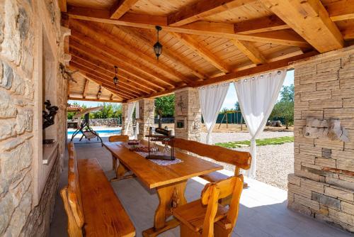 un patio esterno con tavolo e panche in legno di MY DALMATIA - Authentic villa Malou with private swimming pool a Stankovci