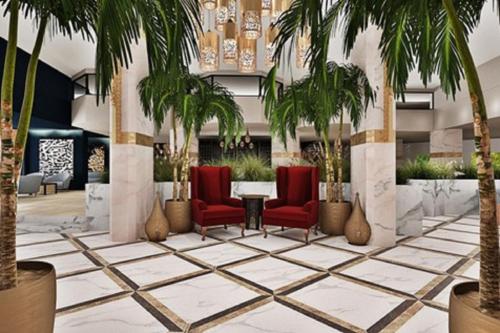 a lobby with palm trees and a table and chairs at Helya Beach Resort in Monastir