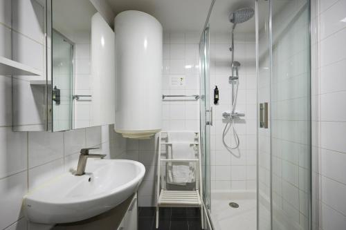 uma casa de banho branca com um lavatório e um chuveiro em Apparthotel des Congrès et Festivals em Cannes