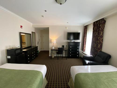 a hotel room with two beds and a television at The Wilshire Grand Hotel in West Orange
