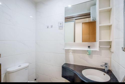 La salle de bains blanche est pourvue d'un lavabo et de toilettes. dans l'établissement Rika Apartement at sky house bsd, à Ciater-hilir