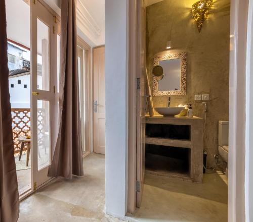 La salle de bains est pourvue d'un lavabo et d'un miroir. dans l'établissement Sharazad Wonders Boutique, à Zanzibar City
