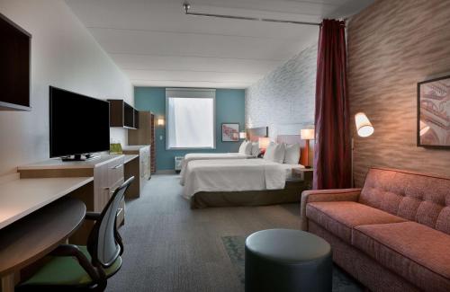 BelmontにあるHome2 Suites By Hilton Charlotte Belmont, Ncのベッドとソファ付きのホテルルーム