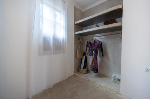 a hallway with a white wall with a window and a shelf at Sharazad Wonders Boutique in Zanzibar City